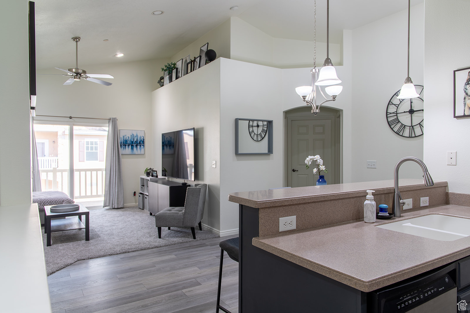 Kitchen featuring hardwood / wood-style flooring, sink, a high ceiling, stainless steel dishwasher, and a kitchen bar