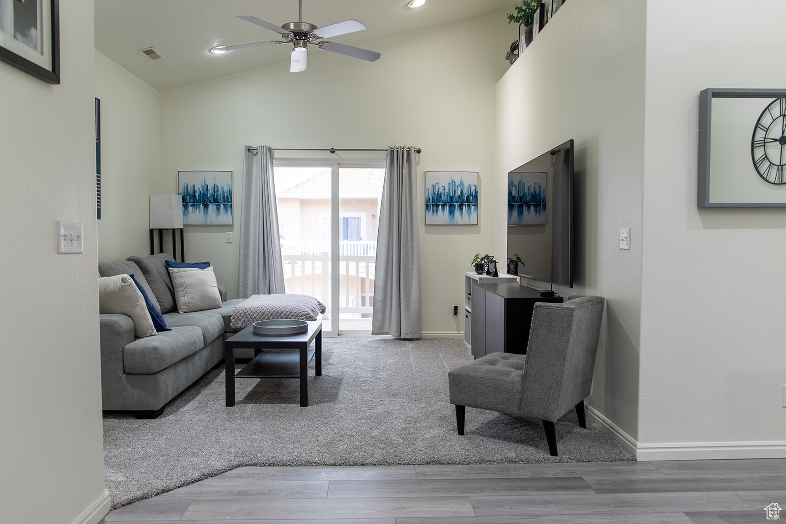 Living room with ceiling fan, high vaulted ceiling, and wood-type flooring