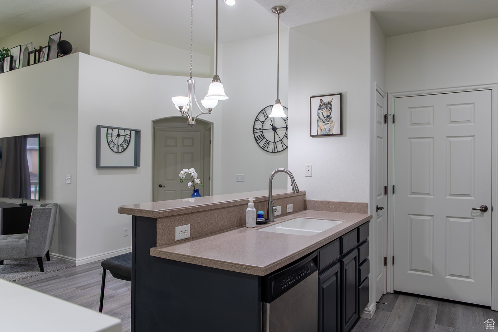 Kitchen with kitchen peninsula, decorative light fixtures, sink, stainless steel dishwasher, and dark wood-type flooring