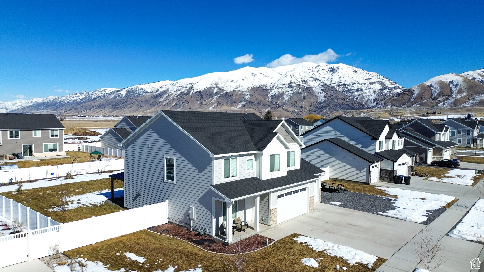 View of front facade featuring driveway, a fenced backyard, a residential view, and a mountain view