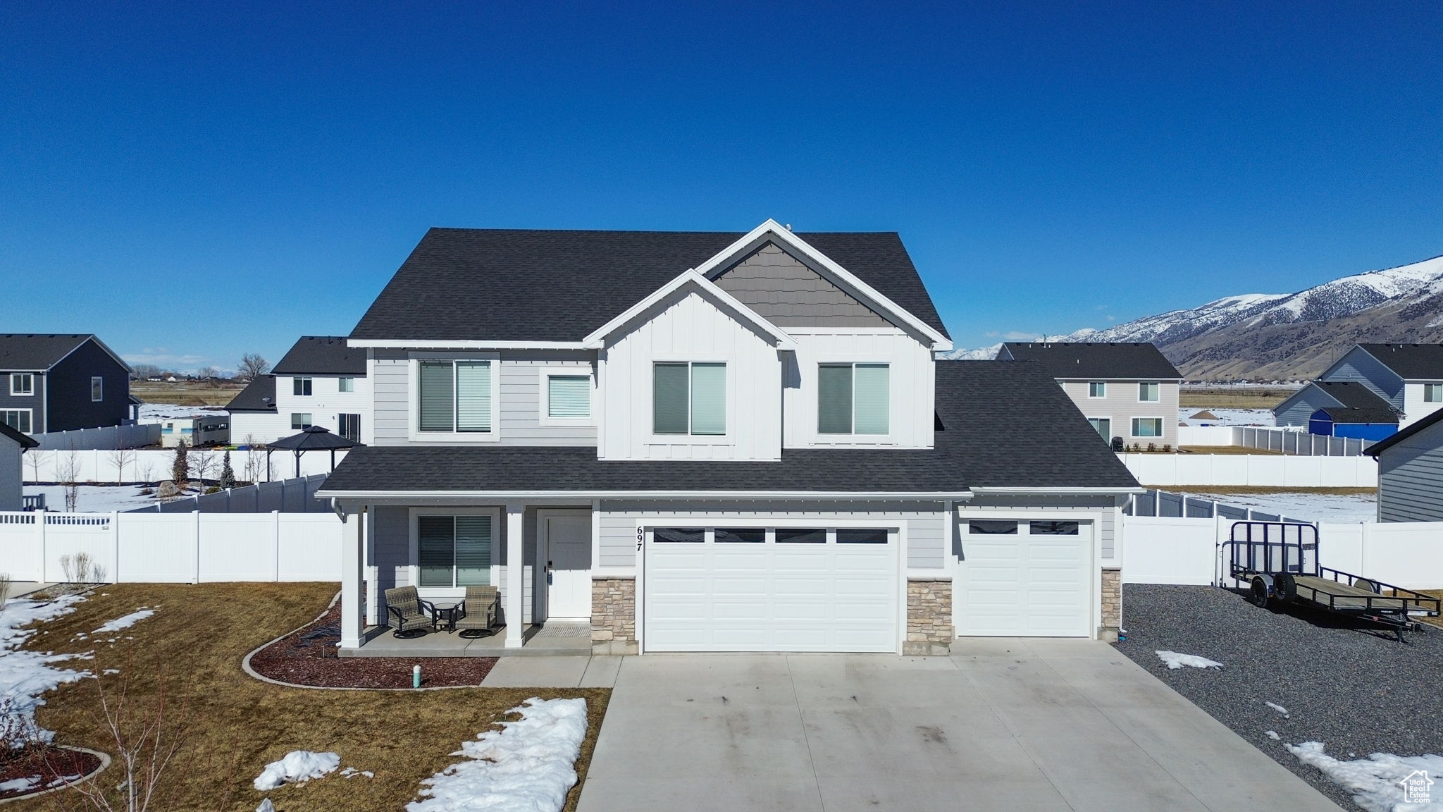 View of front of property featuring concrete driveway, stone siding, fence, a mountain view, and board and batten siding