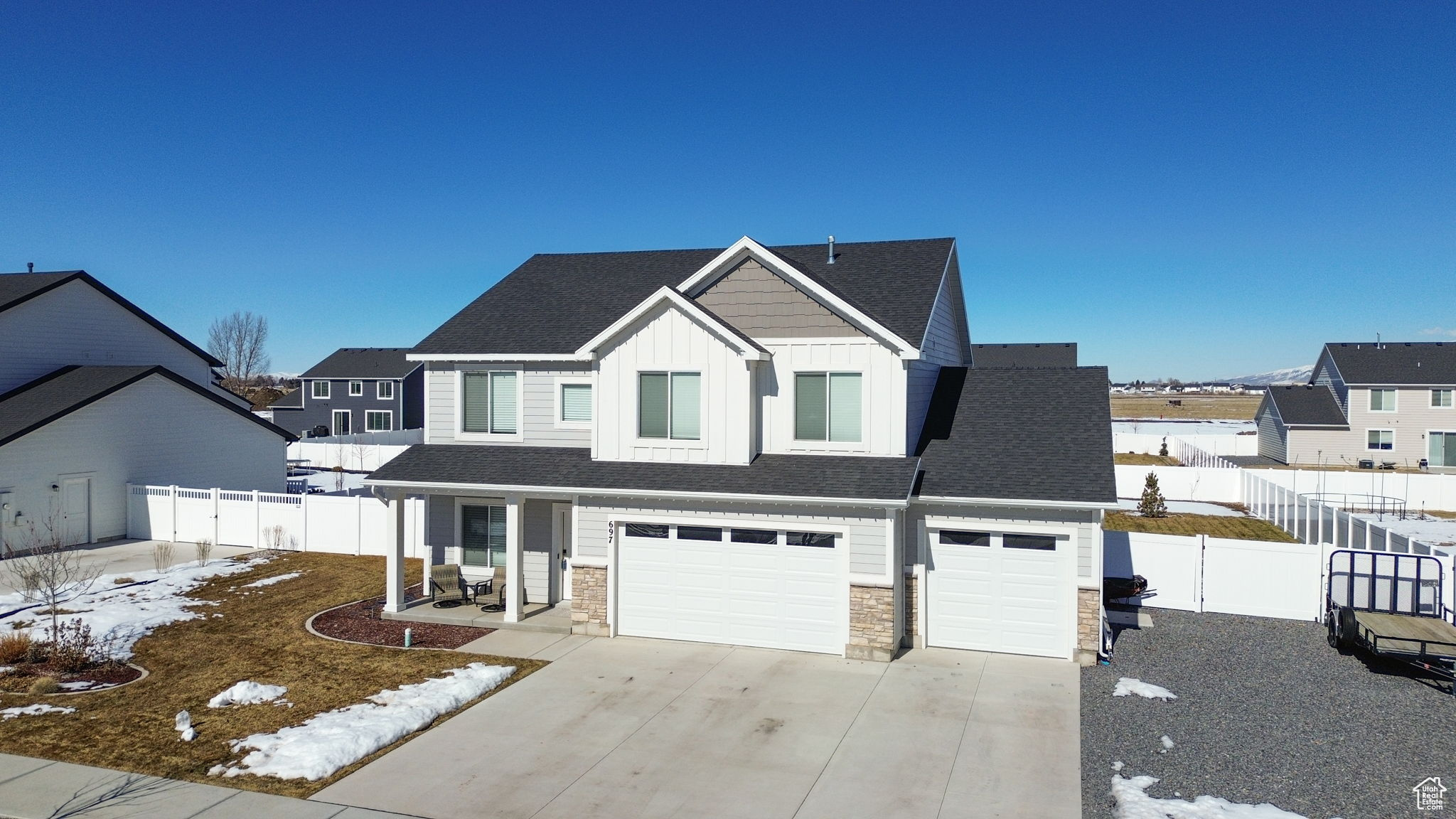 View of front facade with a fenced backyard, driveway, stone siding, a residential view, and board and batten siding