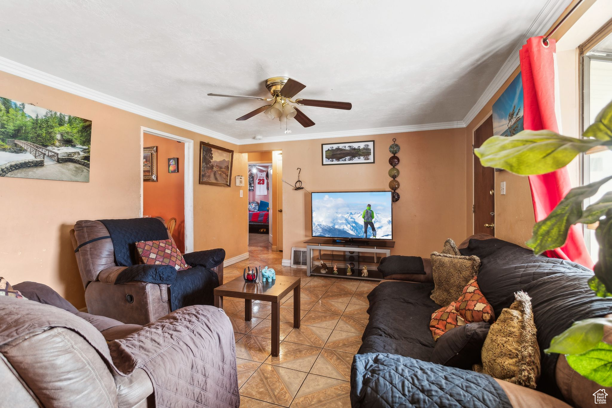 Tiled living room featuring ceiling fan and ornamental molding
