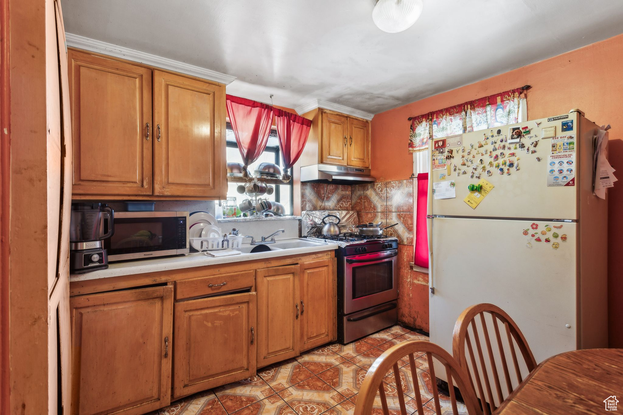 Kitchen with tasteful backsplash, appliances with stainless steel finishes, and light tile patterned floors