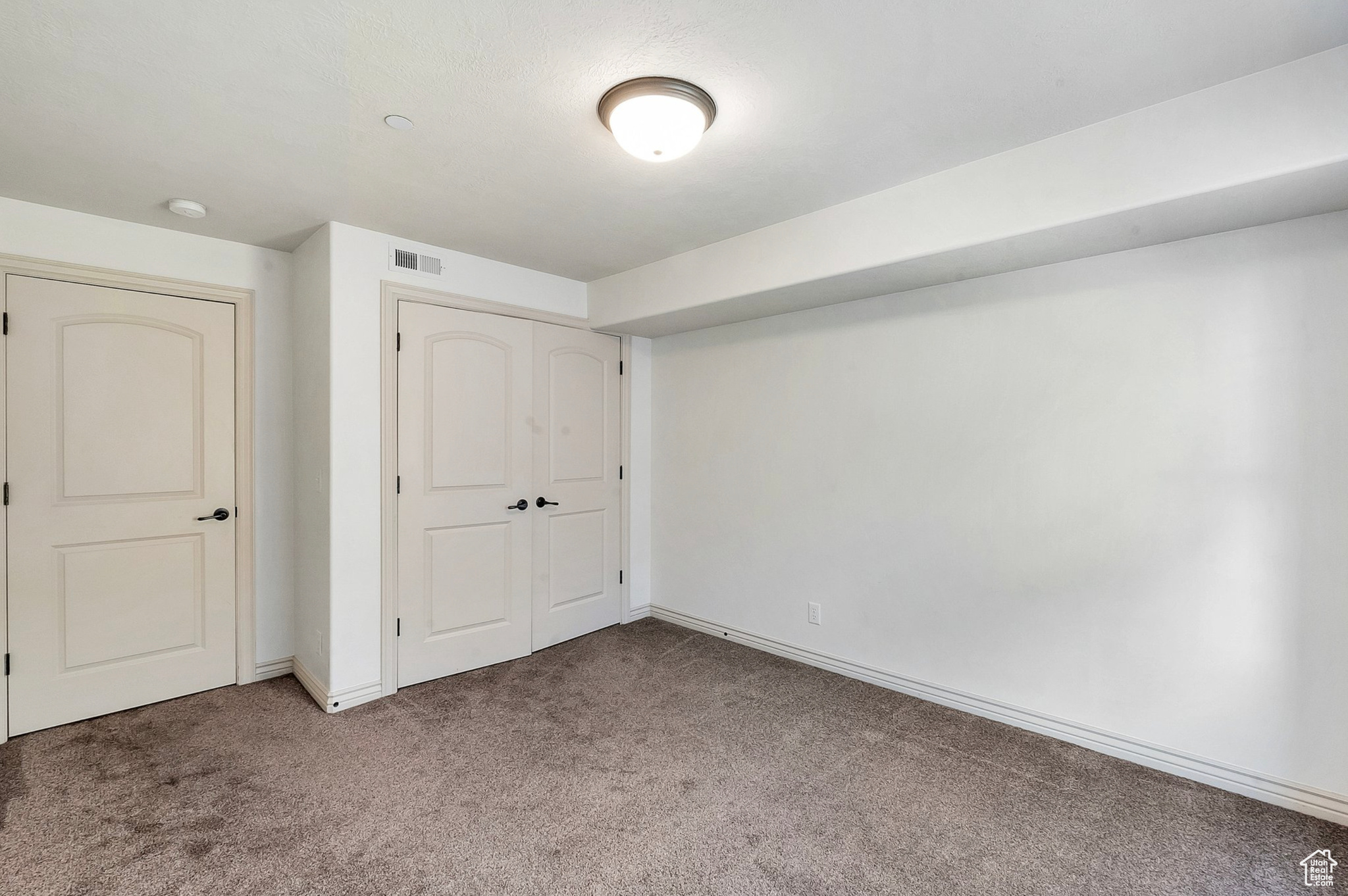 Unfurnished bedroom featuring light carpet and a closet