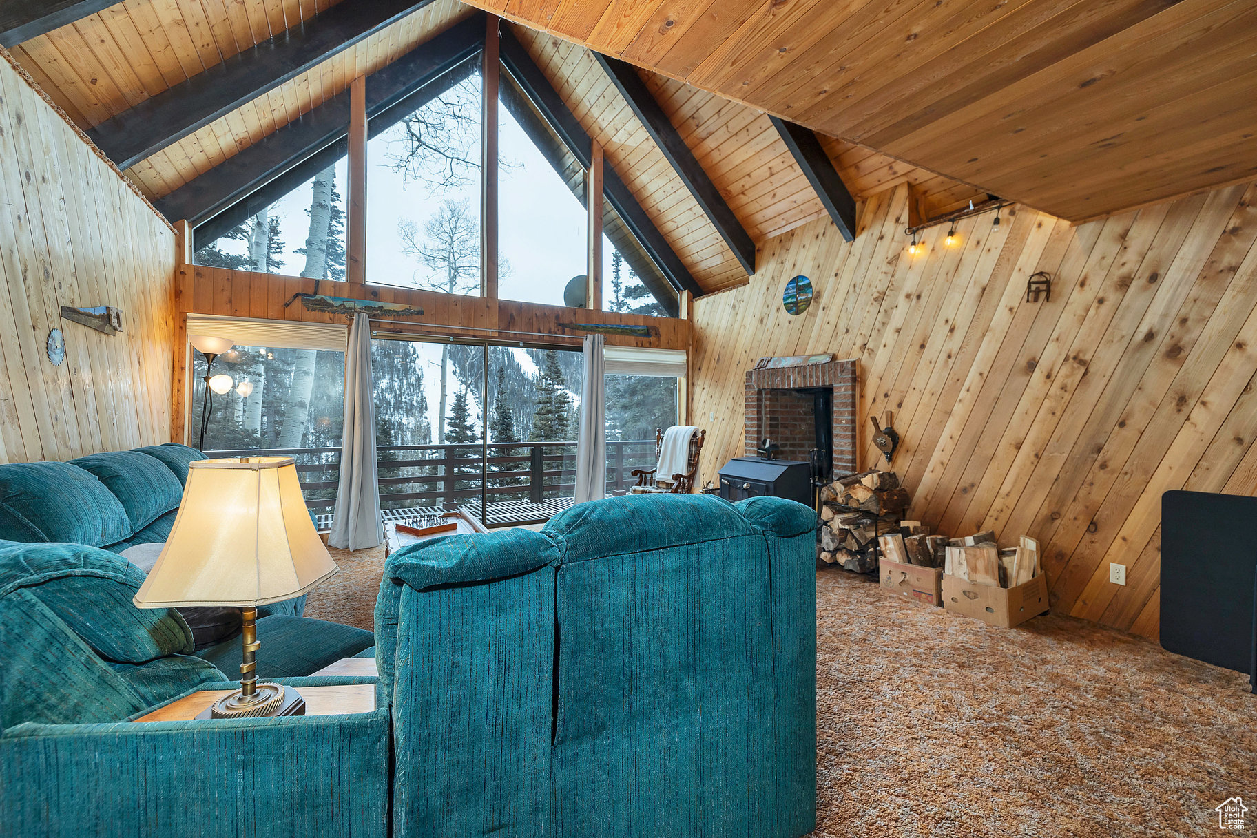Unfurnished living room with beam ceiling, wood ceiling, carpet, and wooden walls