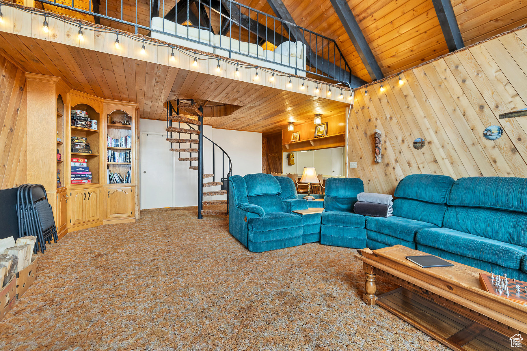 Carpeted living room with wood walls, rail lighting, wood ceiling, and lofted ceiling with beams