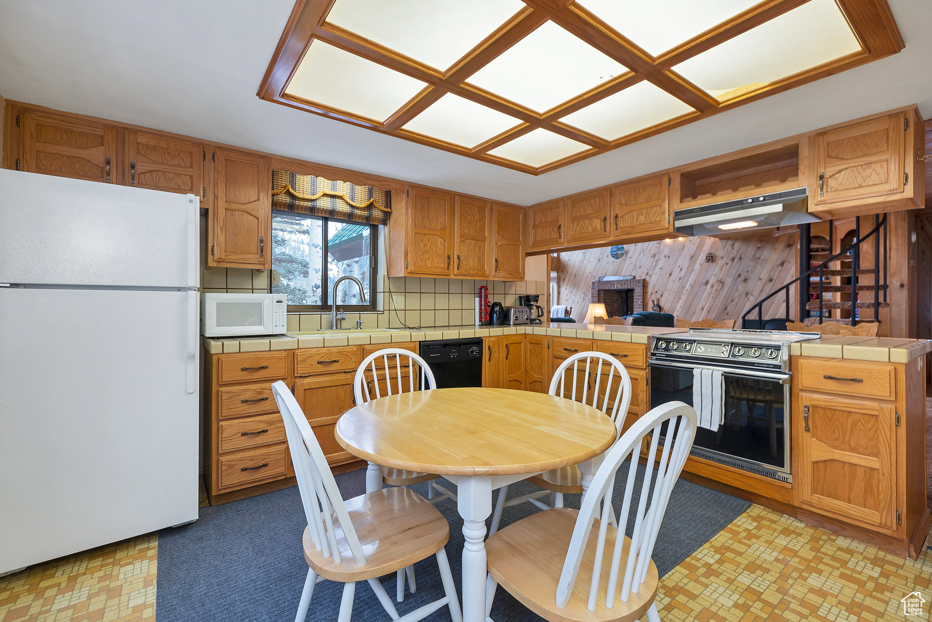 Kitchen with sink, white appliances, kitchen peninsula, and tile countertops