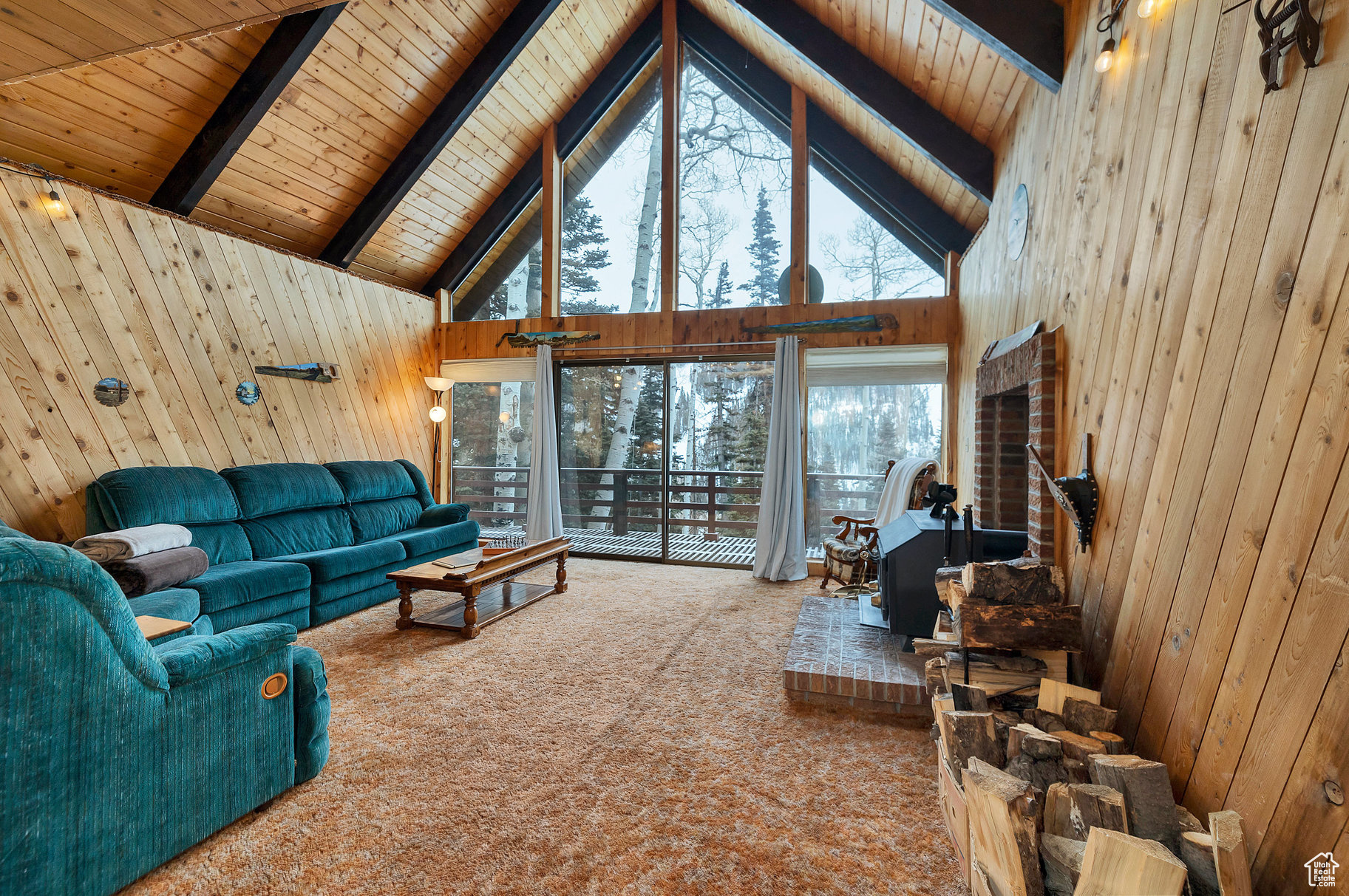 Living room with carpet flooring, wooden walls, high vaulted ceiling, wood ceiling, and beamed ceiling