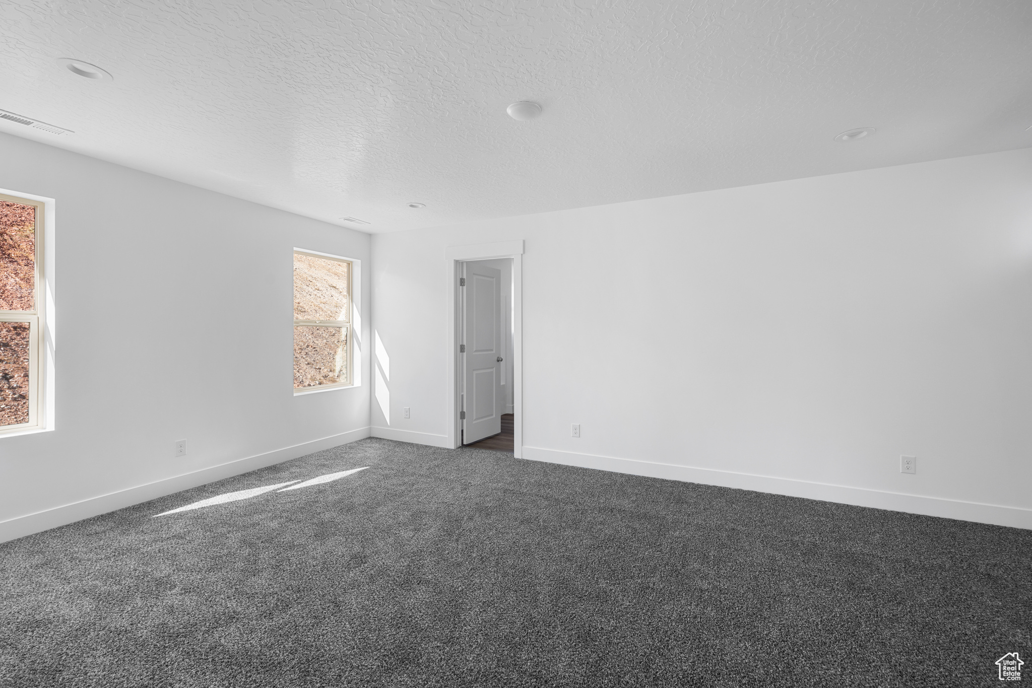 Spare room featuring dark carpet and a textured ceiling