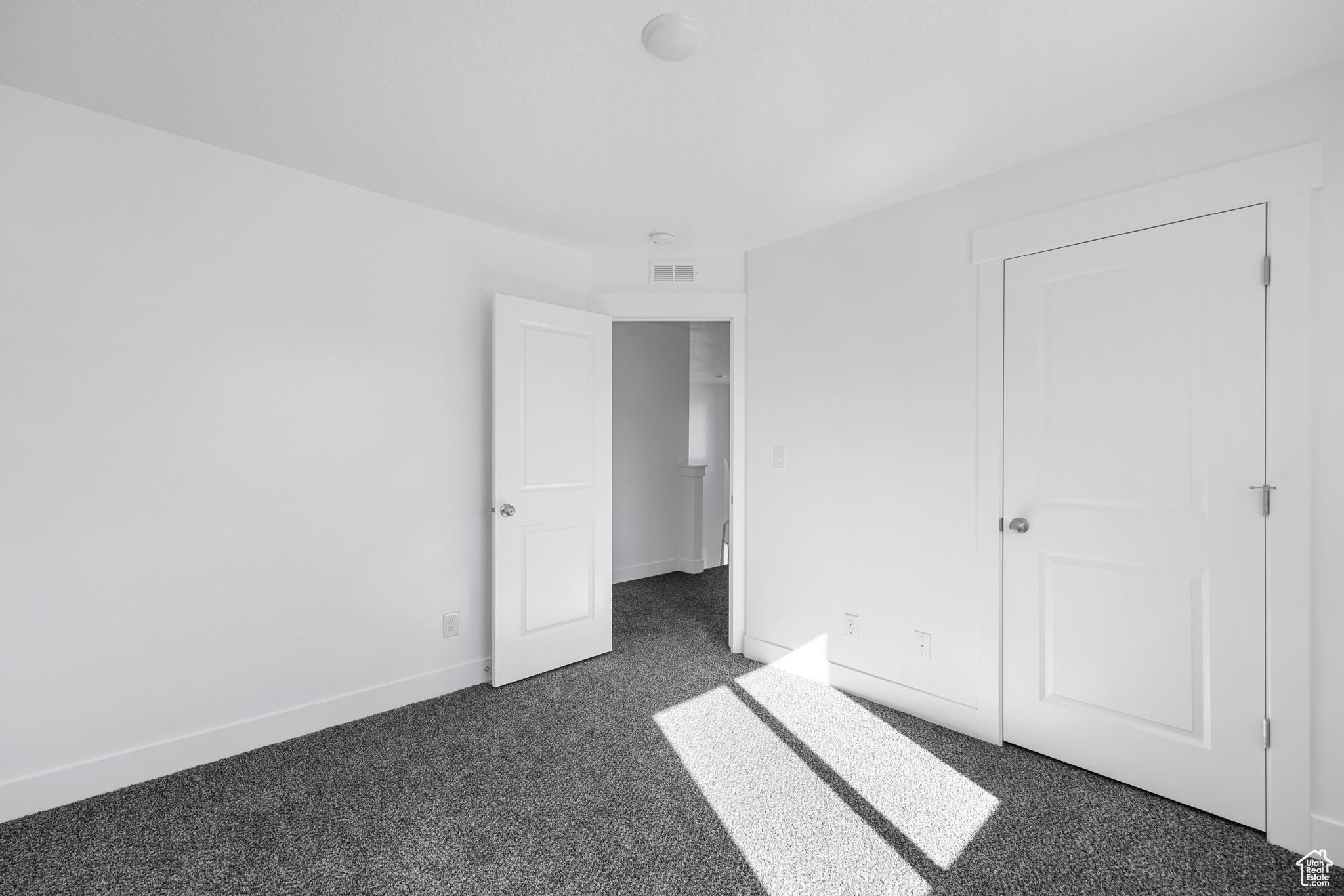 Unfurnished bedroom with dark colored carpet