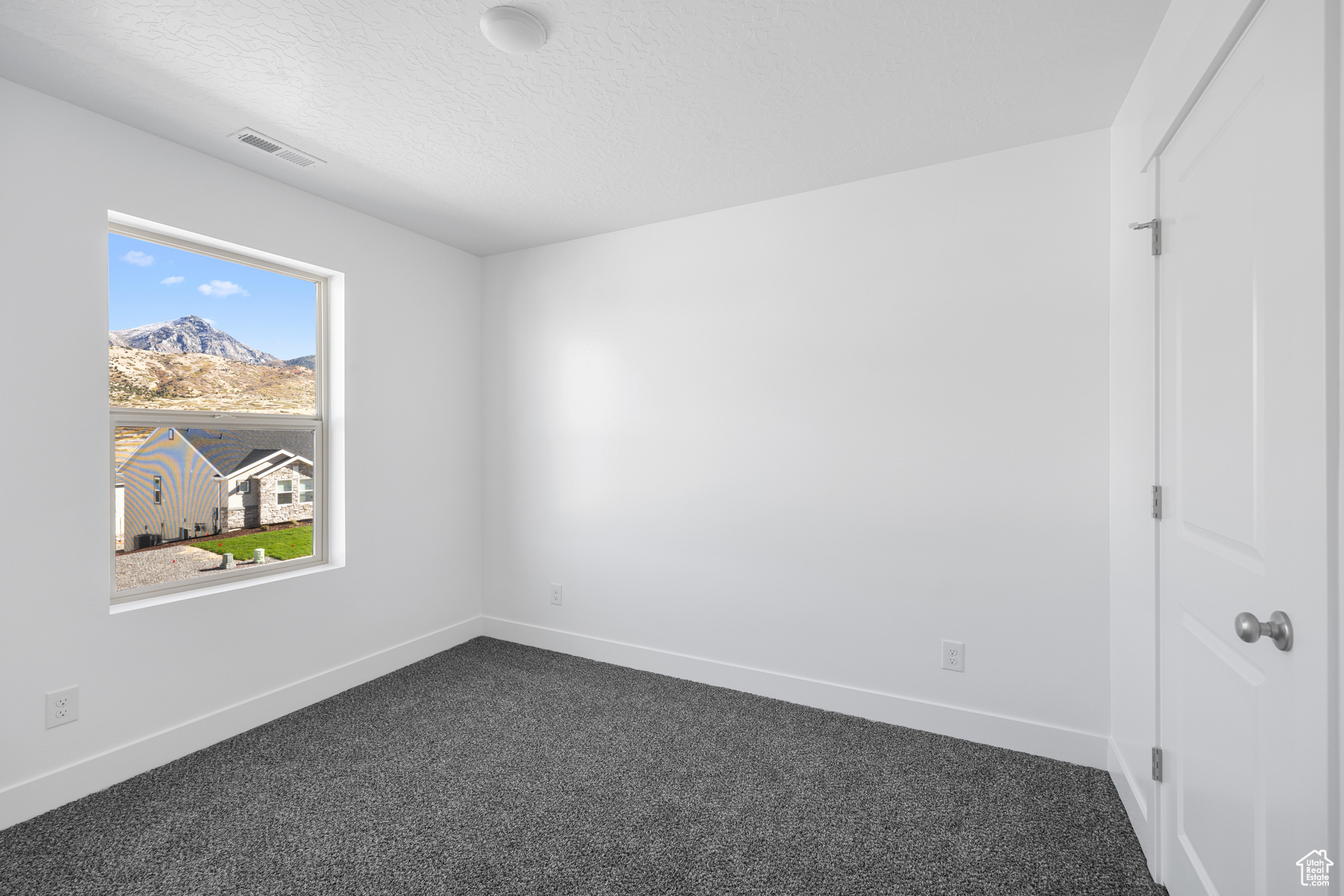 Unfurnished bedroom with dark carpet and a textured ceiling