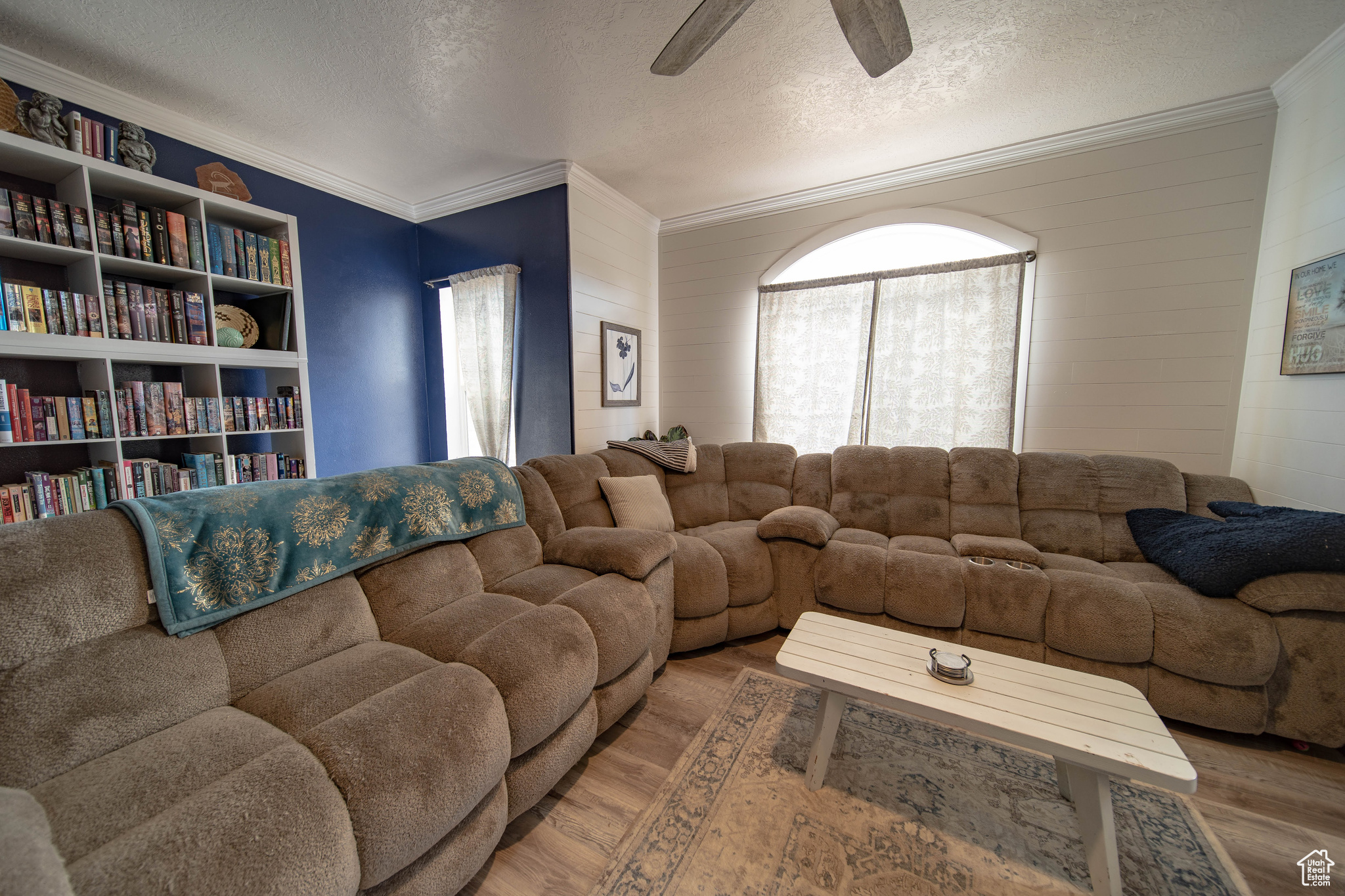 Living room featuring ceiling fan, hardwood / wood-style flooring, crown molding, and a textured ceiling