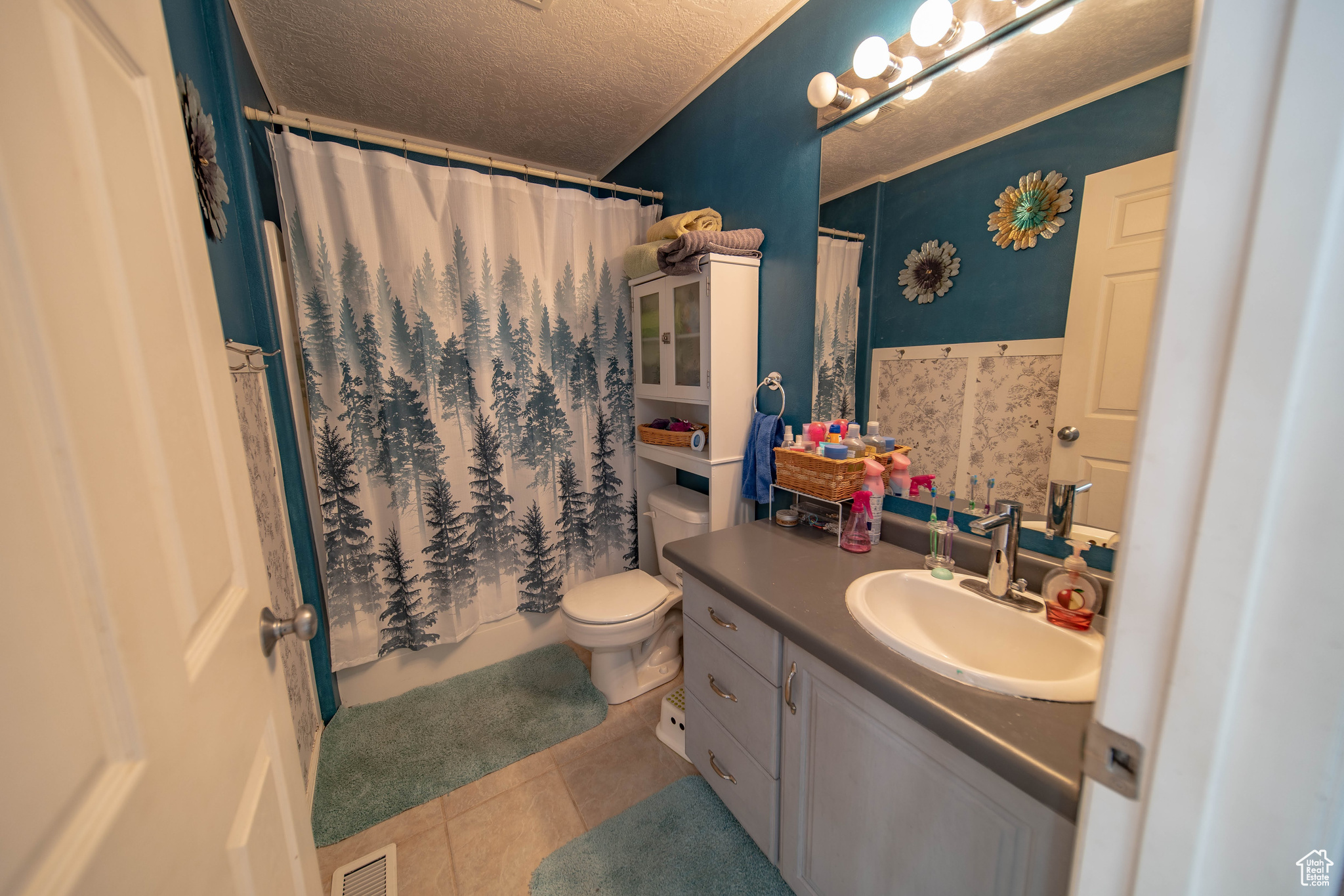 Bathroom with a textured ceiling, toilet, vanity, and tile patterned flooring
