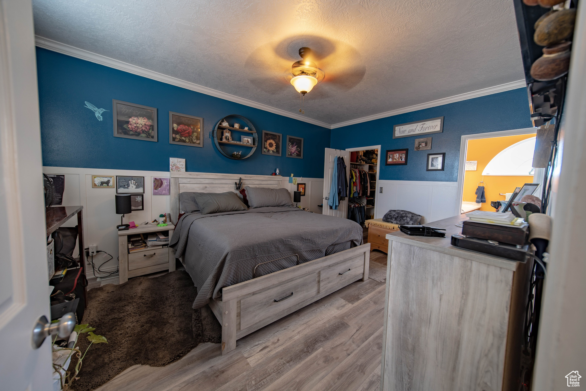 Bedroom with ornamental molding, a closet, a textured ceiling, a spacious closet, and hardwood / wood-style floors