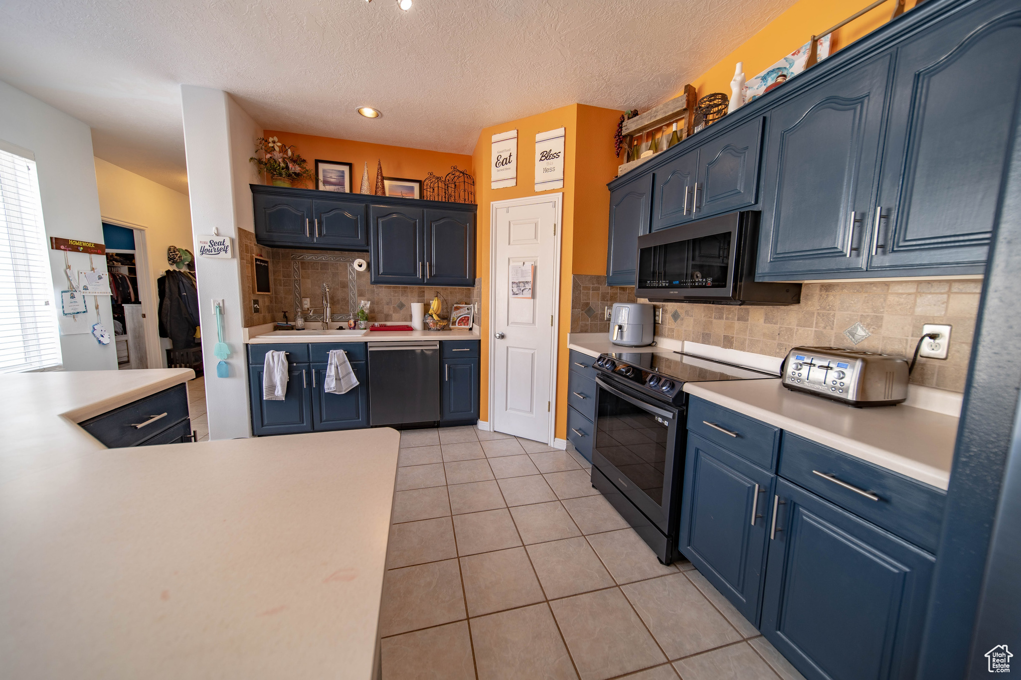 Kitchen featuring blue cabinets, stainless steel appliances, light tile patterned floors, and sink