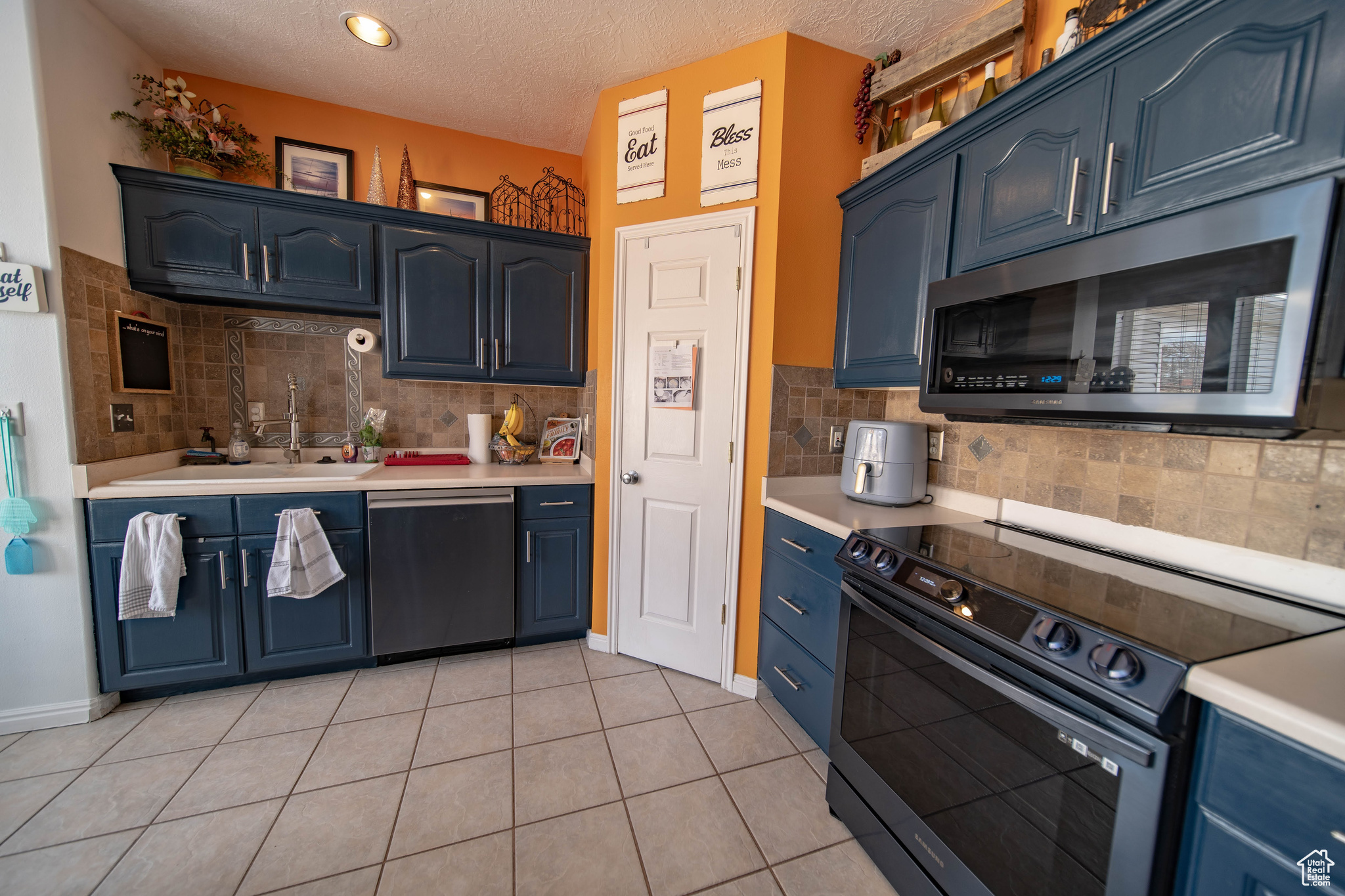 Kitchen featuring light tile patterned flooring, appliances with stainless steel finishes, sink, and blue cabinets