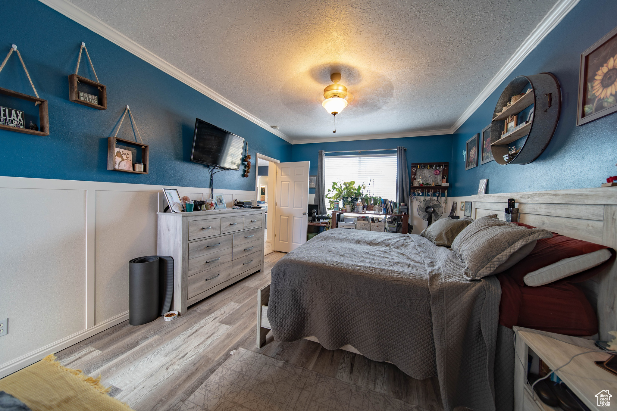 Bedroom with ceiling fan, light hardwood / wood-style floors, crown molding, and a textured ceiling