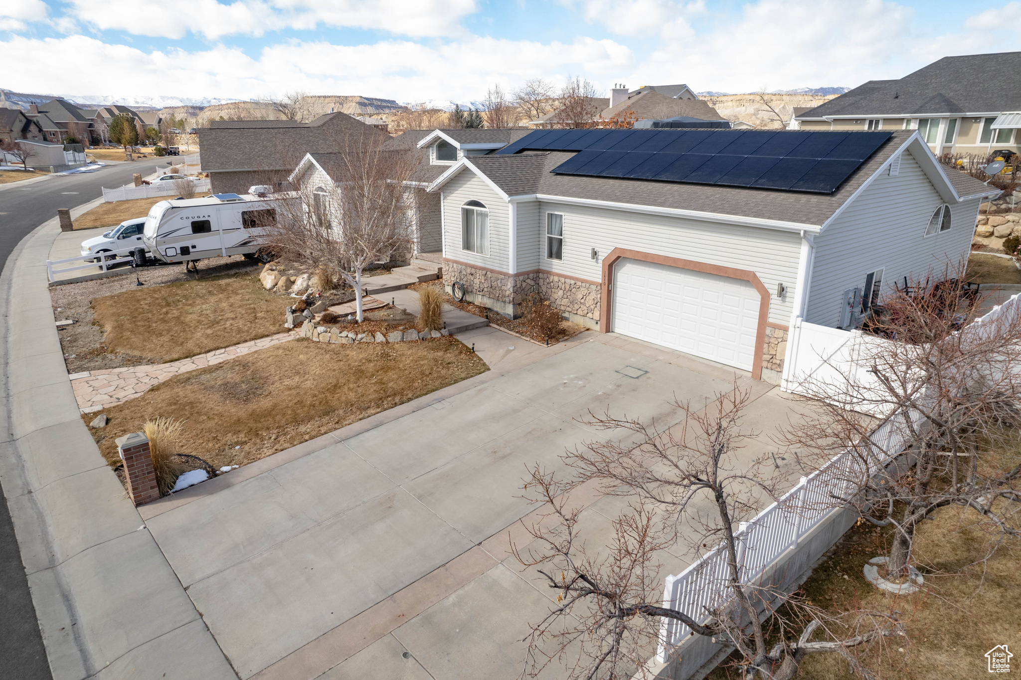 View of front facade featuring a garage and solar panels