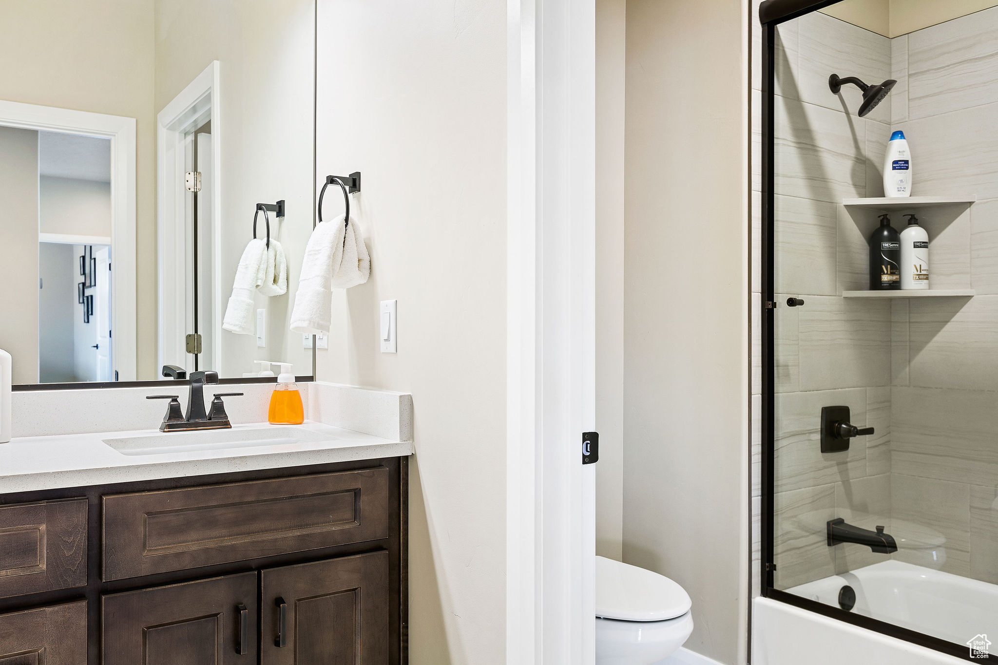 Full bathroom featuring combined bath / shower with glass door, vanity, and toilet