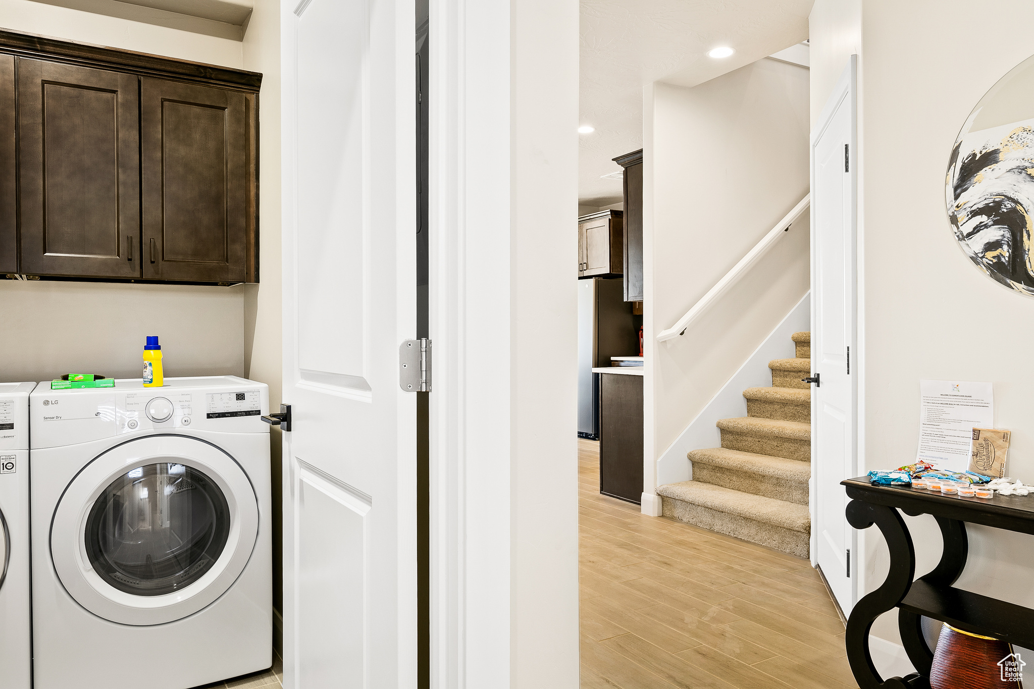 Washroom with light hardwood / wood-style floors, cabinets, and separate washer and dryer