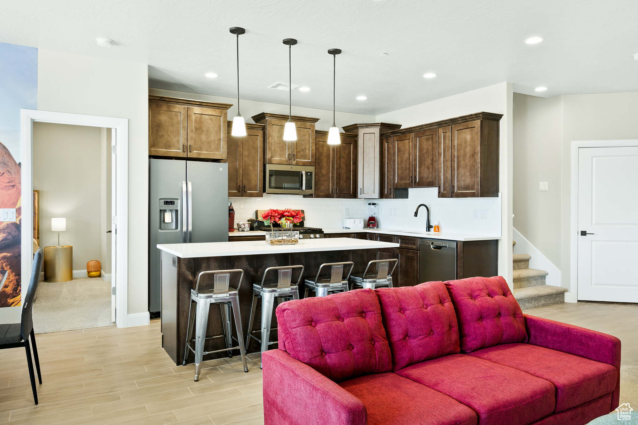 Kitchen featuring backsplash, a center island, a kitchen breakfast bar, stainless steel appliances, and hanging light fixtures