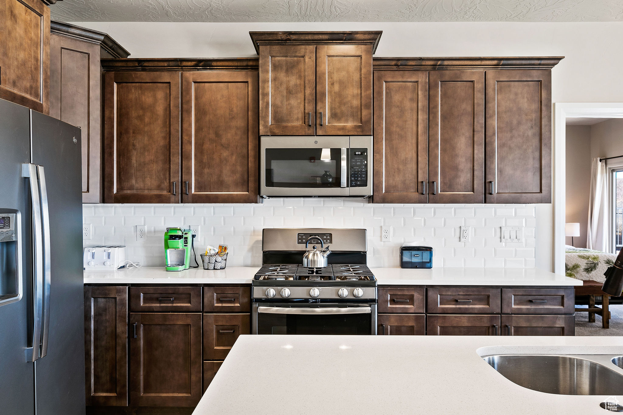 Kitchen featuring sink, appliances with stainless steel finishes, dark brown cabinets, and tasteful backsplash
