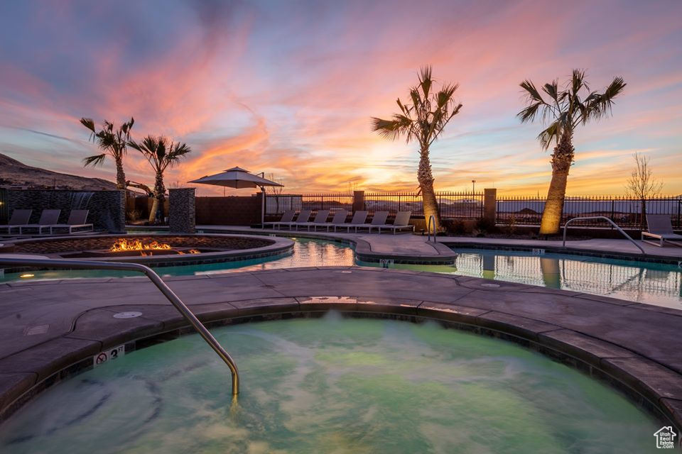 Pool at dusk featuring a community hot tub