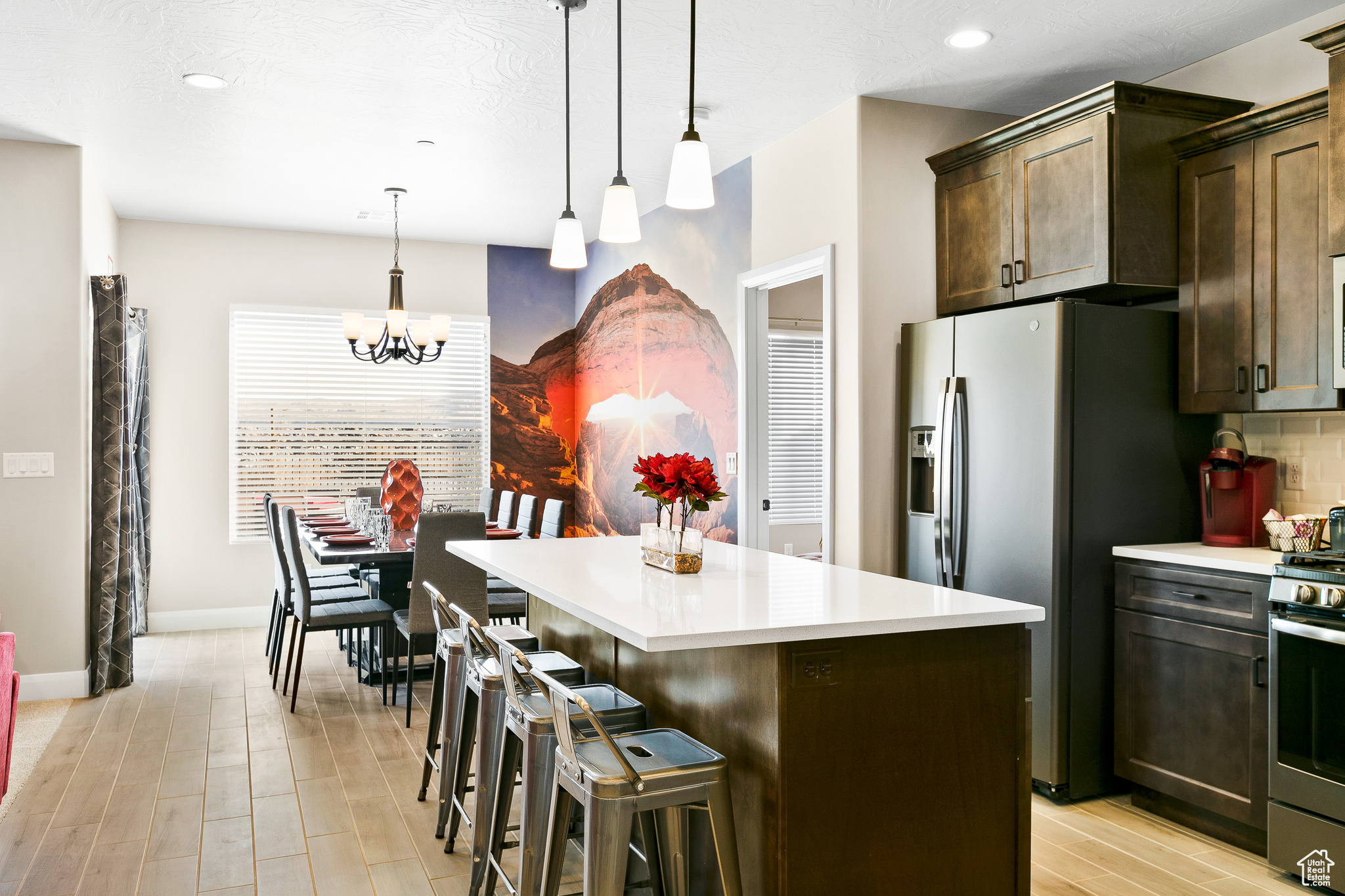Kitchen with appliances with stainless steel finishes, hanging light fixtures, dark brown cabinetry, a kitchen island, and a kitchen bar