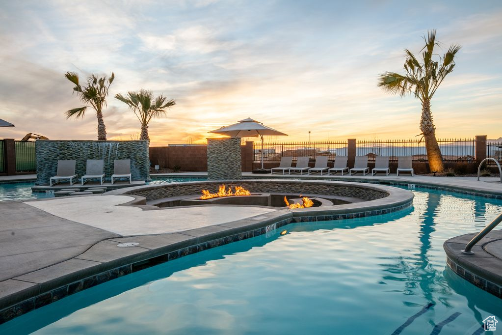 Pool at dusk with a patio and an outdoor fire pit