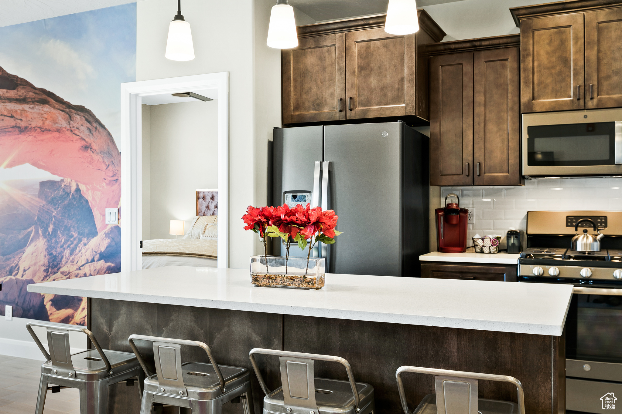 Kitchen featuring appliances with stainless steel finishes, a breakfast bar, pendant lighting, dark brown cabinetry, and decorative backsplash
