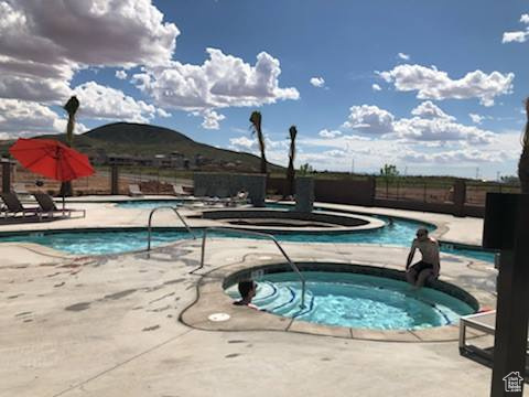 View of pool featuring a patio area, a mountain view, and a community hot tub