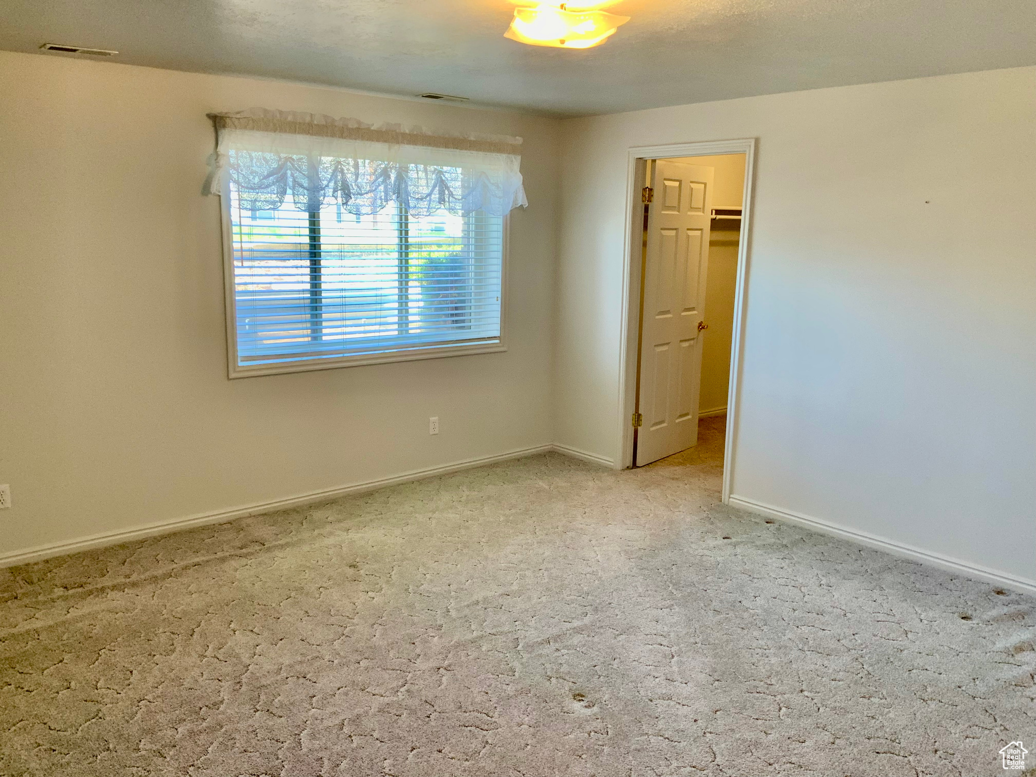 Unfurnished bedroom with a walk in closet and carpet flooring