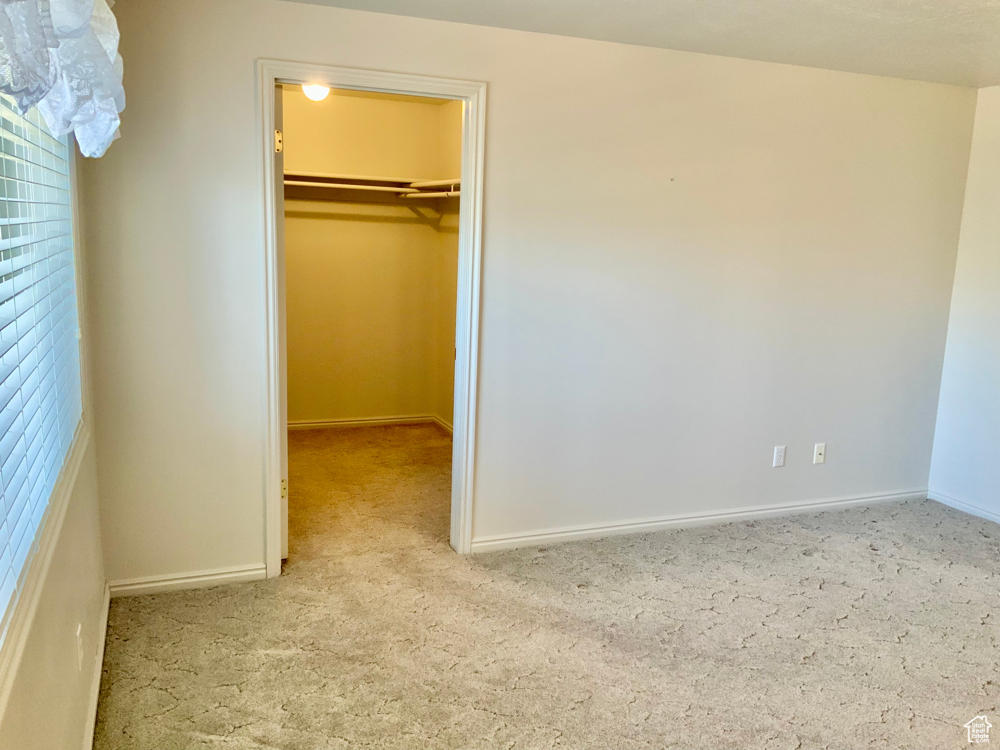 Unfurnished bedroom featuring a closet, light colored carpet, and a walk in closet