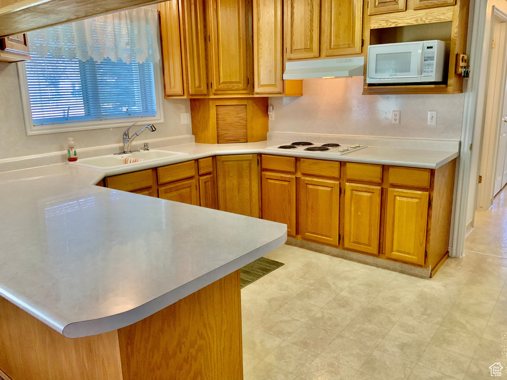 Kitchen featuring white appliances, sink, and kitchen peninsula