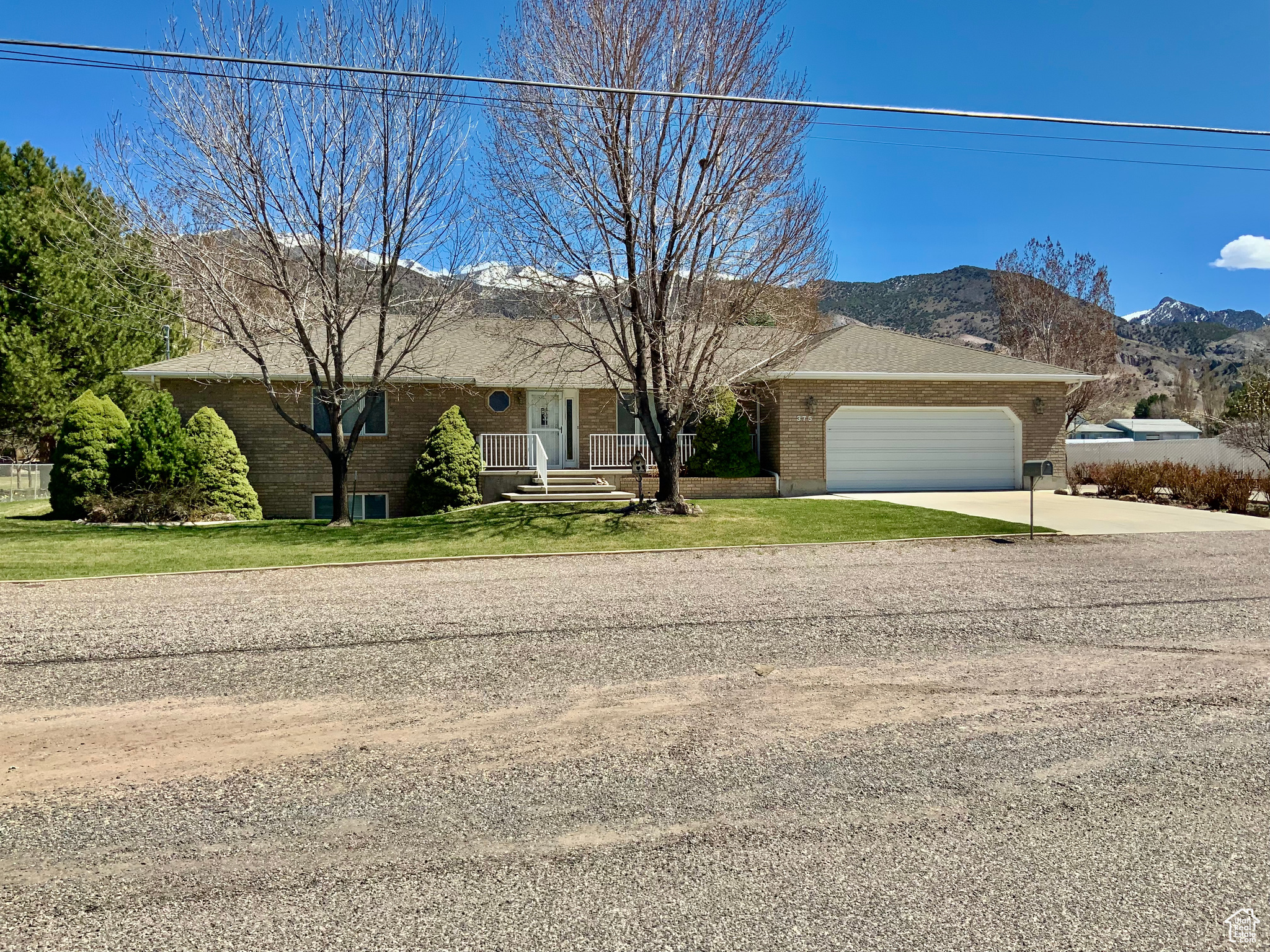 Ranch-style house with a mountain view, a front lawn, and a garage