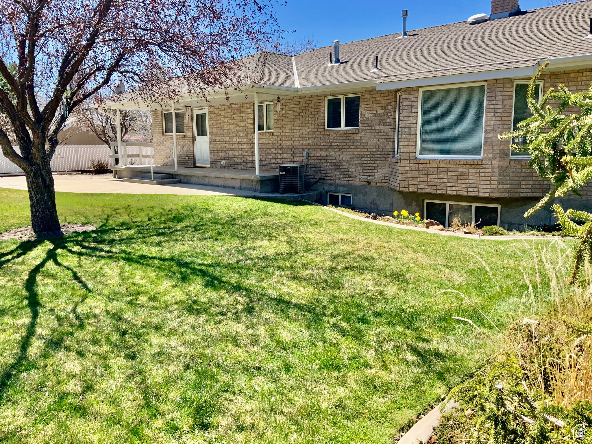 Rear view of house featuring a patio, a yard, and central air condition unit