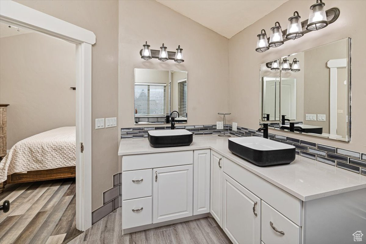 Bathroom with hardwood / wood-style flooring, backsplash, and vanity