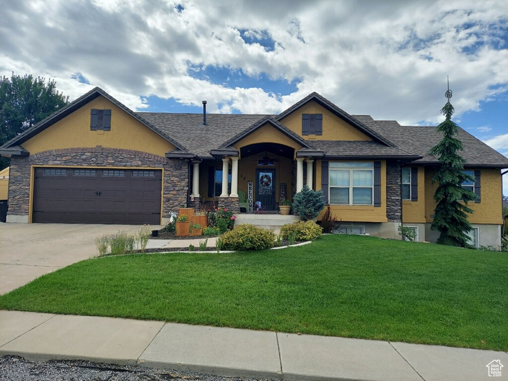 View of front facade featuring a garage and a front yard during the summer