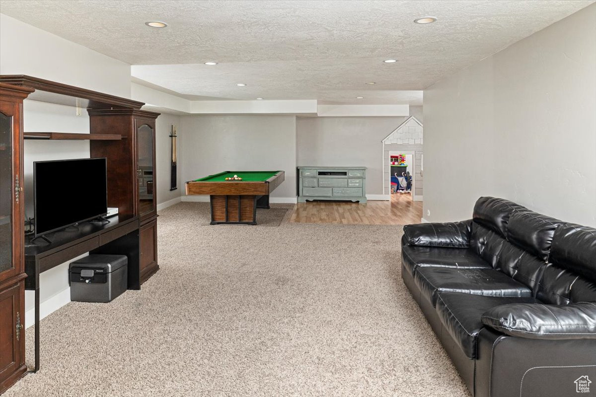 Living room with billiards, a textured ceiling, and light colored carpet