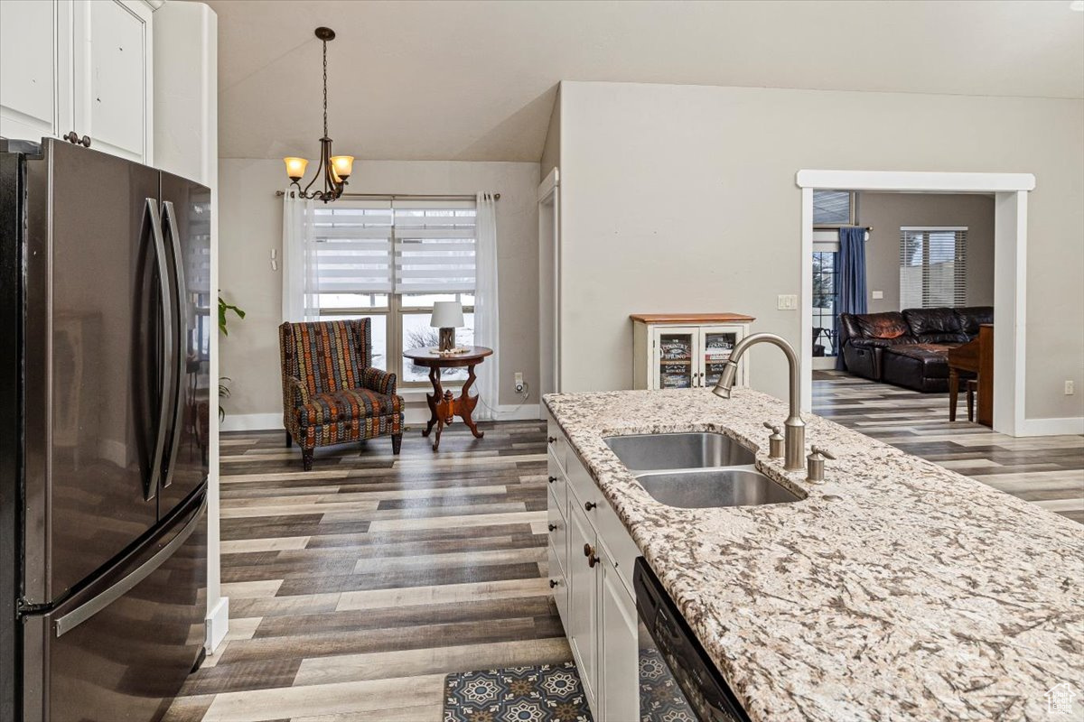 Kitchen featuring wood-type flooring, refrigerator, sink, white cabinetry, and light stone countertops