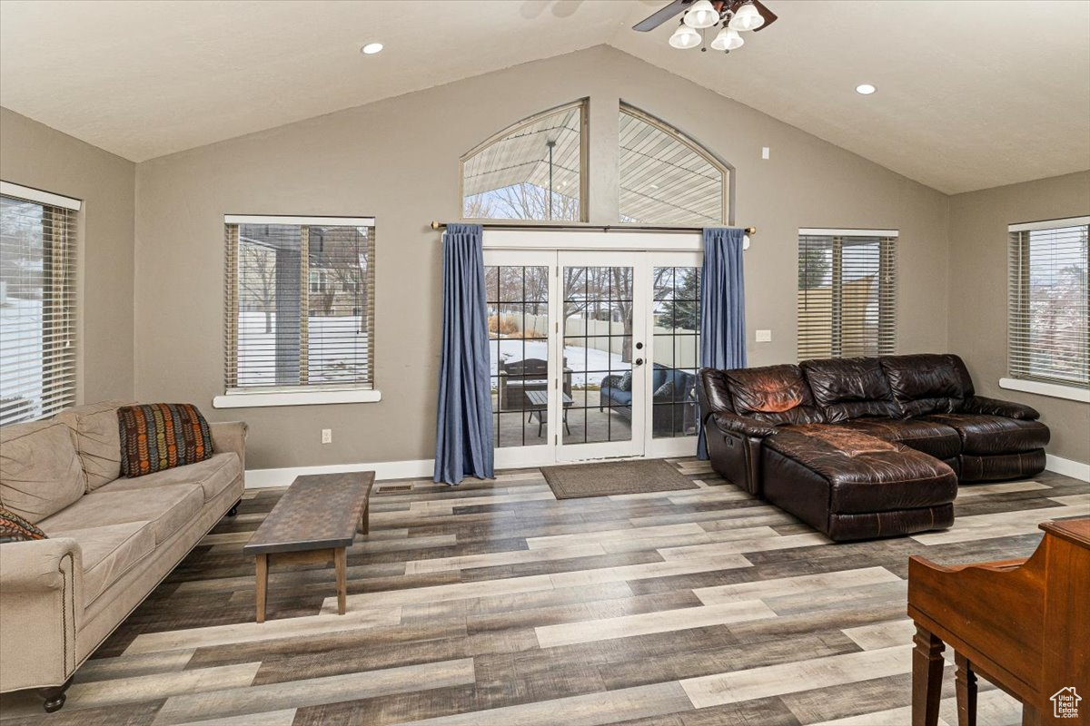 Living room with french doors, vaulted ceiling, ceiling fan, and wood-type flooring