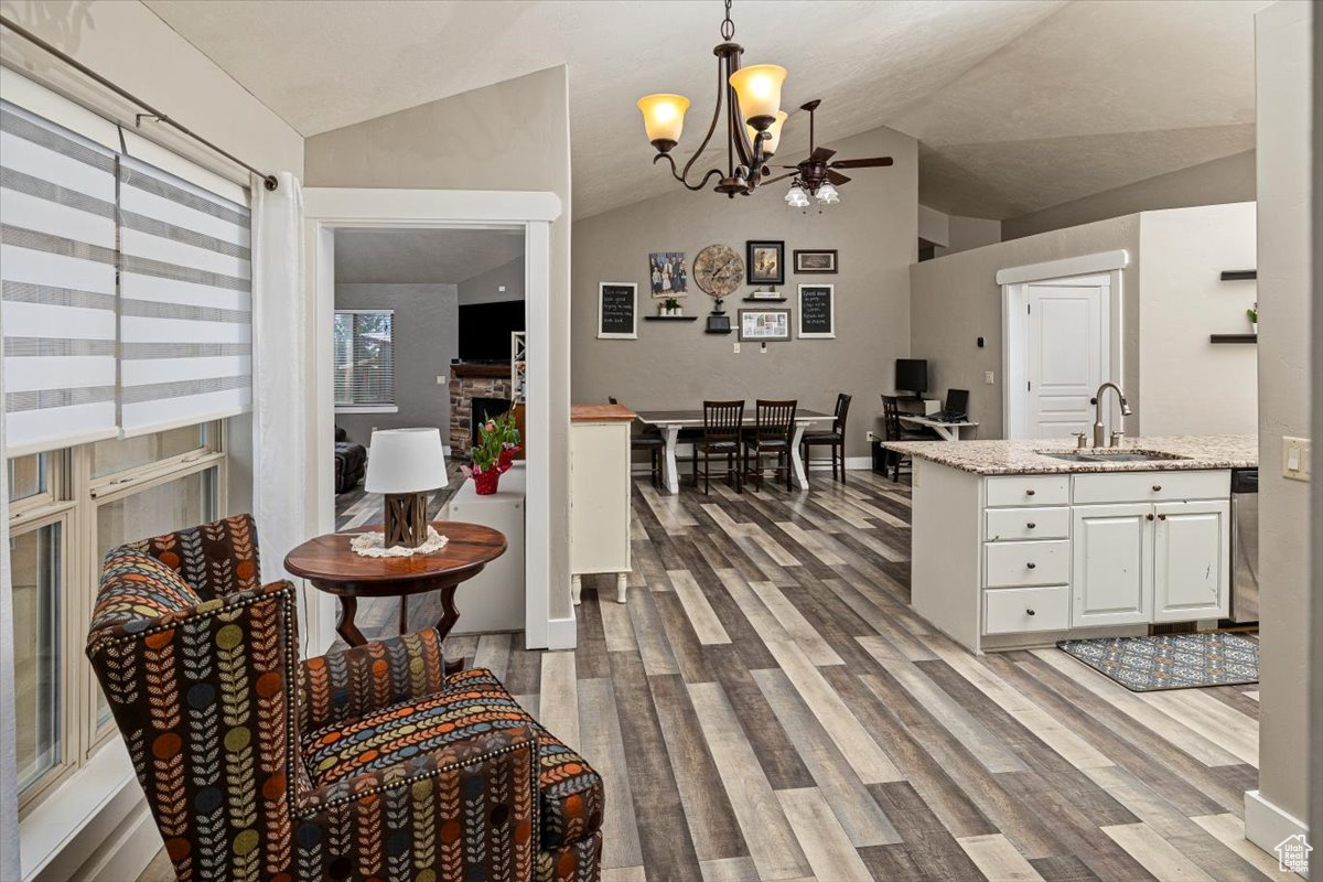Kitchen with white cabinetry, a fireplace, lofted ceiling, sink, and pendant lighting
