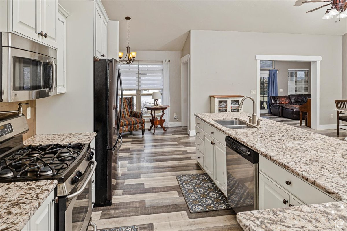 Kitchen with white cabinets, hanging light fixtures, stainless steel appliances, and sink
