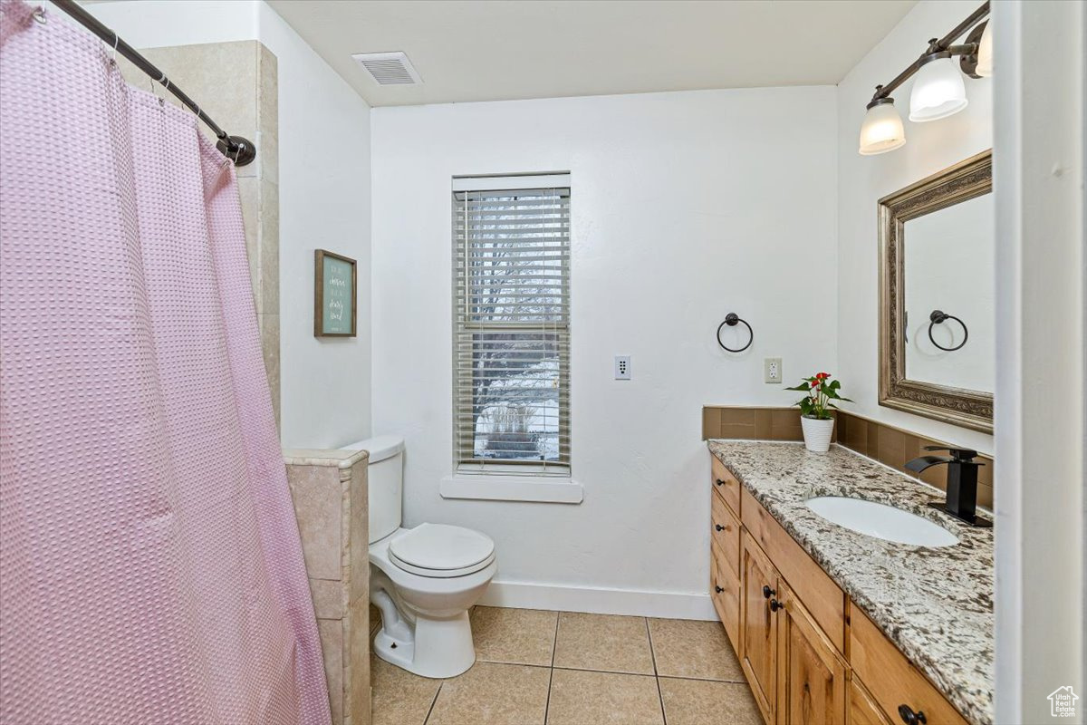 Bathroom featuring toilet, tile patterned flooring, vanity, and walk in shower
