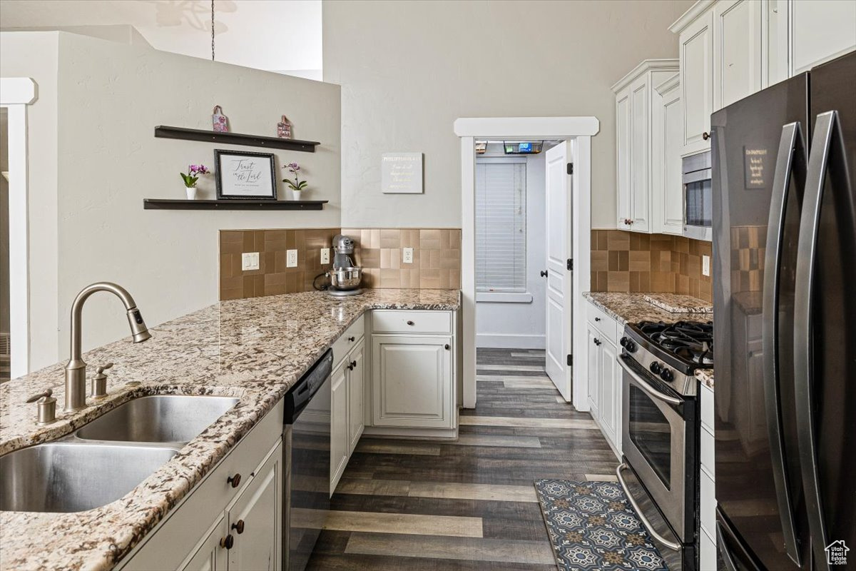 Kitchen with sink, appliances with stainless steel finishes, white cabinets, and light stone counters