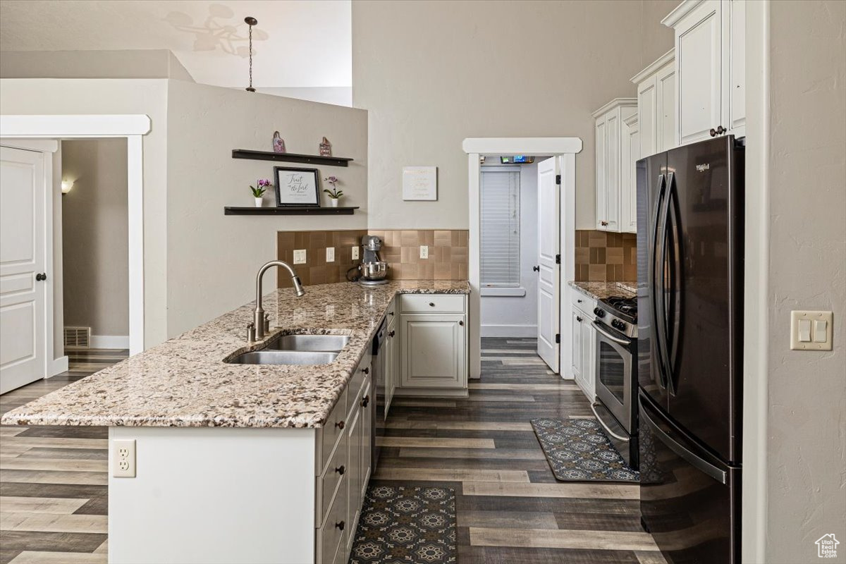 Kitchen featuring appliances with stainless steel finishes, light stone counters, sink, white cabinetry, and kitchen peninsula