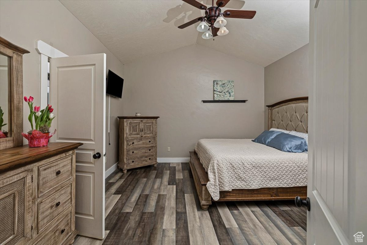 Bedroom with dark wood-type flooring, lofted ceiling, and ceiling fan