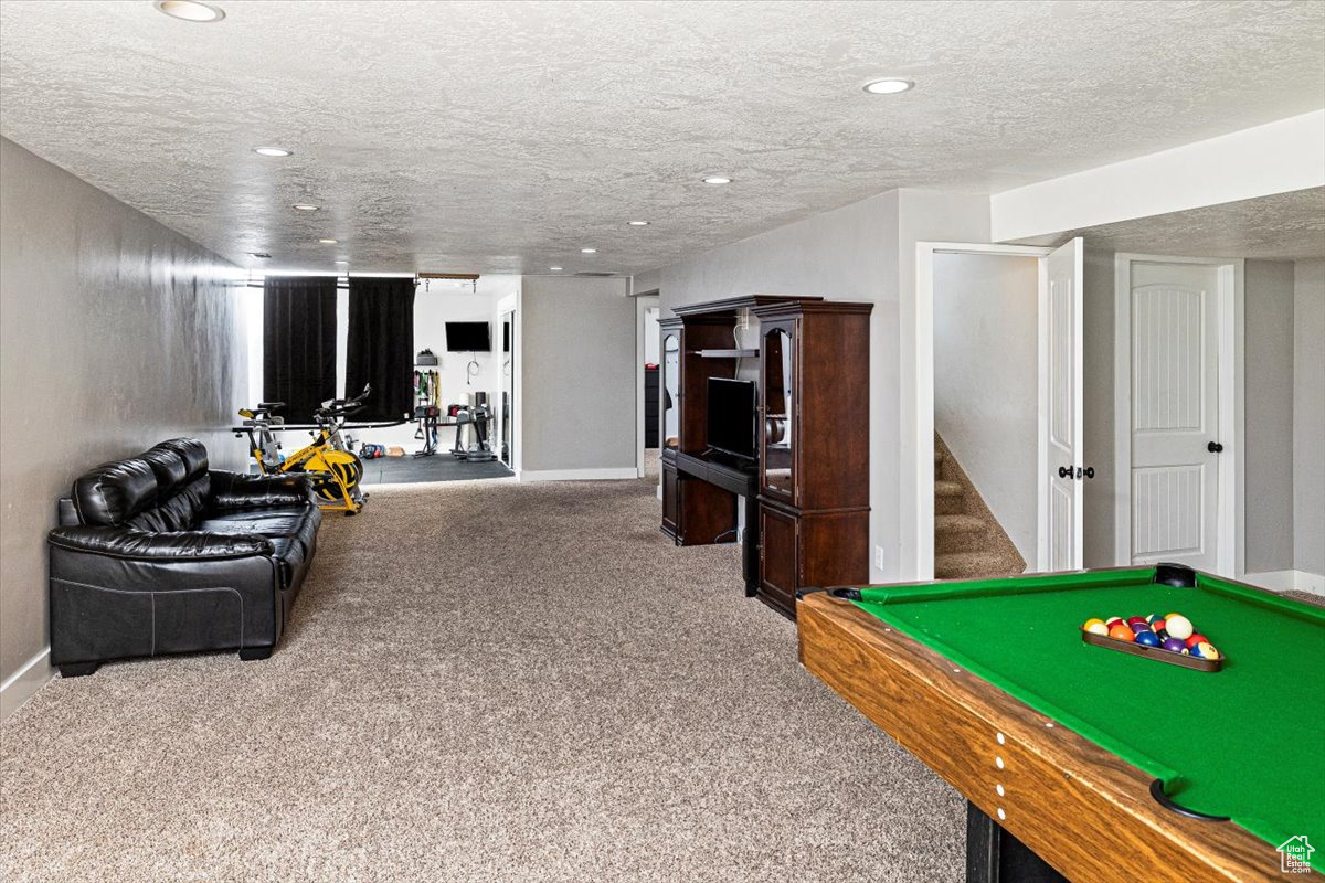 Playroom featuring carpet floors, pool table, and a textured ceiling