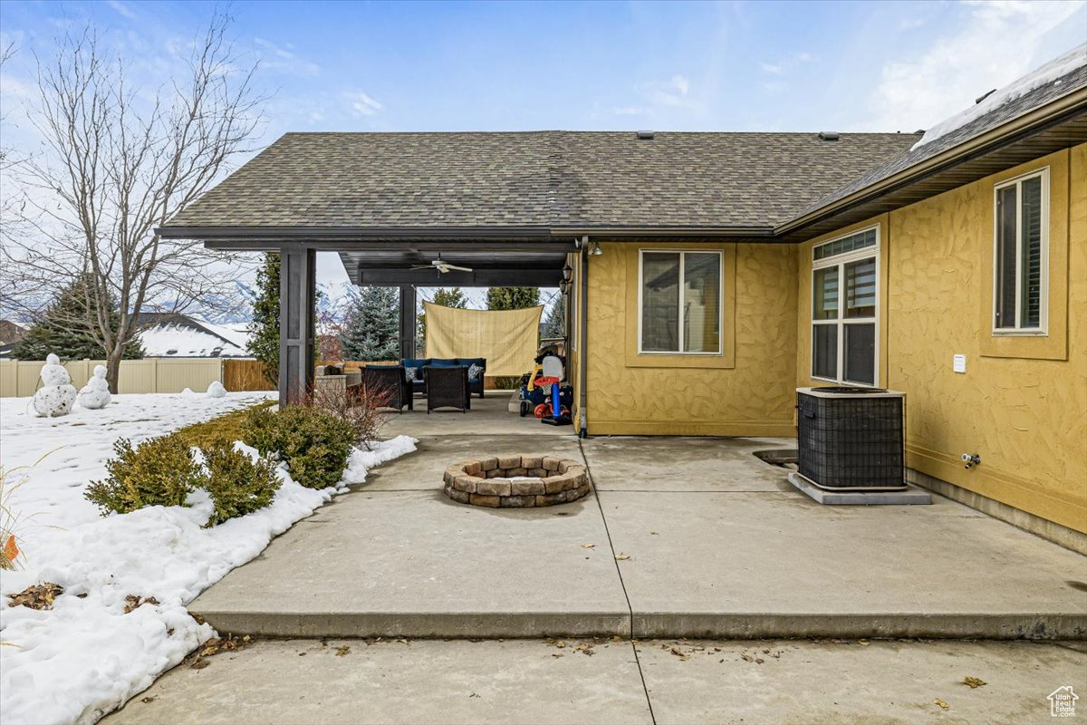 View of patio with an outdoor fire pit, central AC unit, and fence